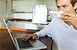 Young man using laptop in kitchen