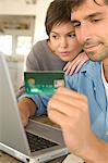 Young couple using credit card on internet