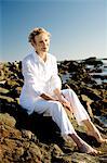 Haute femme assise sur les rochers du bord de mer