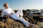 Senior woman lying on seaside rocks
