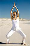 Senior woman doing yoga on the beach