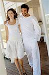 Smiling couple embracing, walking on wooden terrace