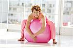Young smiling woman resting on big pink ballon