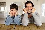 Father and son smiling for the camera, with hands on cheeks