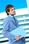 Young businessman holding file, side view