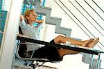 Young businesswoman resting in office with legs on desk