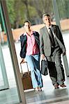 Mature man and young woman walking with suitcase at corridor