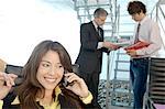 Businesswoman using mobile phone with colleagues in background