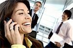 Businesswoman using mobile phone with colleagues in background