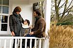 Fille debout et souriant avec ses parents dans un balcon