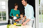 Mid adult man and a young woman preparing food with their son