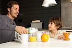 Mid homme adulte prenant son petit déjeuner avec son fils dans la cuisine