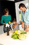 Mid adult man and a young woman preparing food with their son in a kitchen