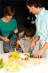 Mid adult man and a young woman preparing food with their son