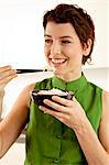 Gros plan d'une femme adulte mid, manger du riz avec des baguettes