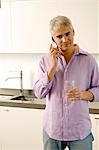 Älterer Mann sprechen auf einem Handy in der Küche