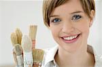 Portrait of a young woman holding paintbrushes