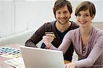 Mid adult man and a young woman using a laptop and holding a credit card