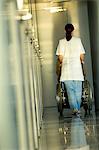 Rear view of a female doctor pushing a patient sitting in a wheelchair