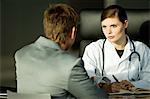 Ärztin mit einem männlichen Patienten in ihrem Büro am Schreibtisch sitzend