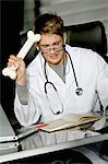 Nahaufnahme eines männlichen Arztes sitzend am Schreibtisch und einen Knochen