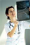 Femme médecin examinant un rapport aux rayons x et souriant