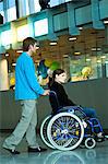 Side profile of a mid adult man pushing a young woman sitting in a wheelchair