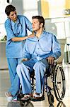 Patient masculin assis dans un fauteuil roulant et une femme médecin debout à côté de lui