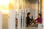 Two businessmen sitting in a corridor and talking with each other