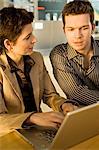 Businesswoman using a laptop with a businessman sitting beside her