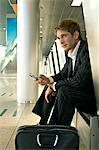 Businessman sitting at an airport lounge and operating a mobile phone