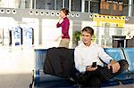 Businessman holding a mobile phone and sitting at an airport lounge