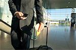 Mid section view of a businessman using a mobile phone at an airport