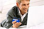 Mid adult man working on a laptop and holding a credit card