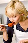 Close-up of a young woman smelling tomato sauce