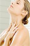 Close-up of a young woman applying moisturizer on her neck