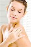 Close-up of a young woman applying moisturizer on her shoulder