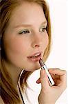 Close-up of a young woman applying lipstick