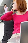 Young woman using a laptop and talking on a mobile phone