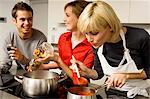 Two young women and a young man preparing food in the kitchen