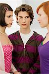 Close-up of a teenage boy standing with two young women