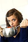 Portrait of a young woman holding a saucepan and looking surprised