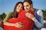 Portrait of a couple hugging a heart shaped cushion