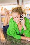 Woman lying on the kitchen counter and talking on a mobile phone