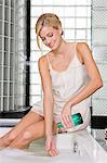 Woman pouring liquid soap in a bathtub