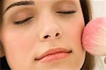 Woman applying blusher on her face