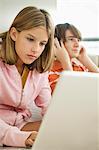 Girl working on a laptop and boy listening headphones