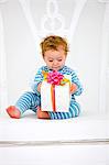 Baby Boy hält ein Geschenk im Lehnstuhl
