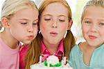 Gros plan de trois filles, souffler les bougies sur un gâteau d'anniversaire