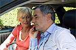 Man with his wife in a car and talking on a mobile phone